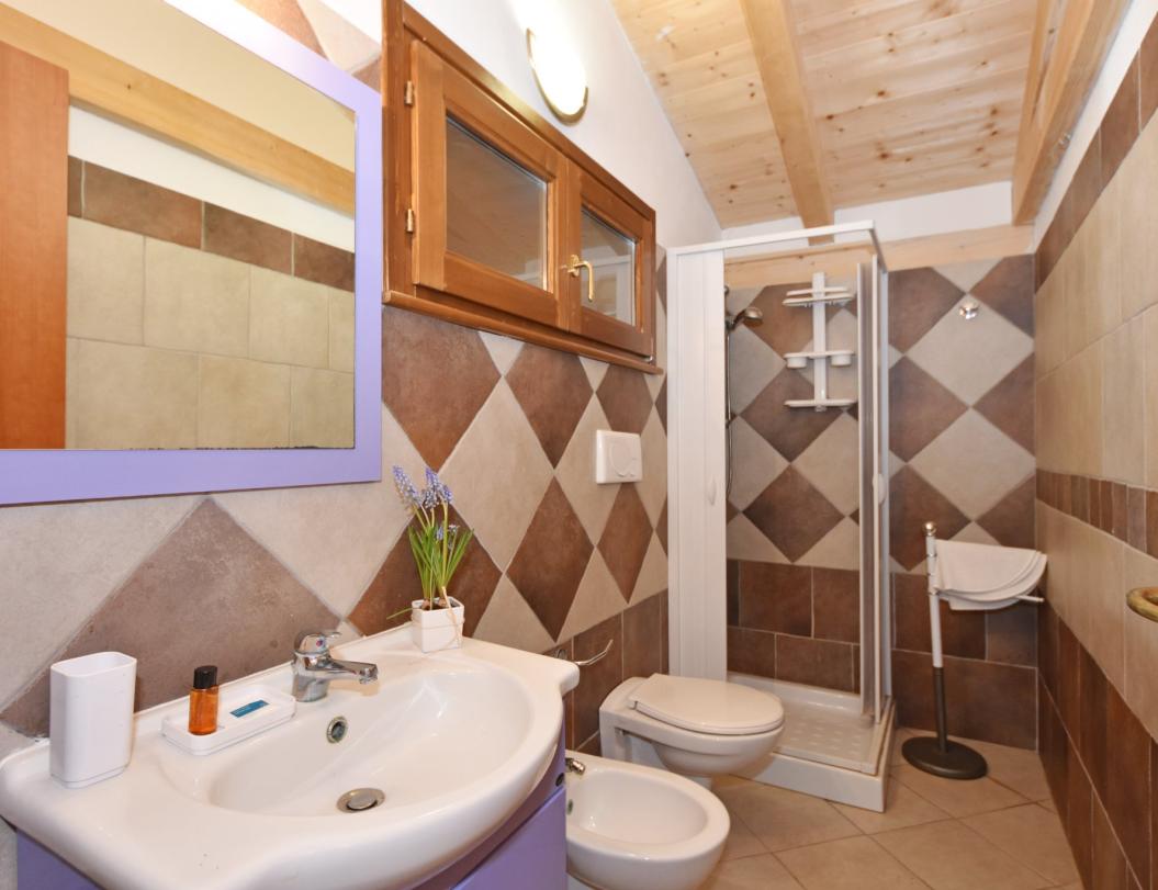 Gemütliches Badezimmer mit Dusche, Waschbecken, Bidet und großem Spiegel.